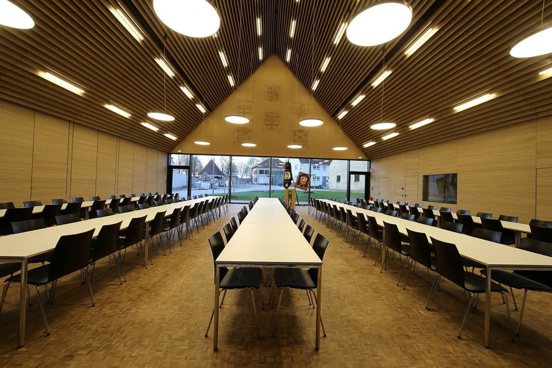 Großer Sitzungssaal mit Holzlamellendecke und langen Tischreihen im Bürgerzentrum Möttingen