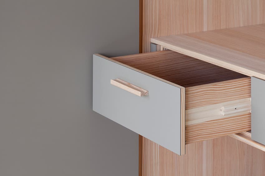 Geöffnete Schublade aus Massivholz mit grauer Front und Holzgriff