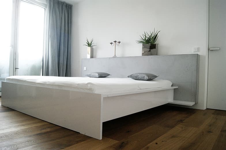 Weißes Bett mit breitem Kopfteil in Betonoptik und integriertem Schrank